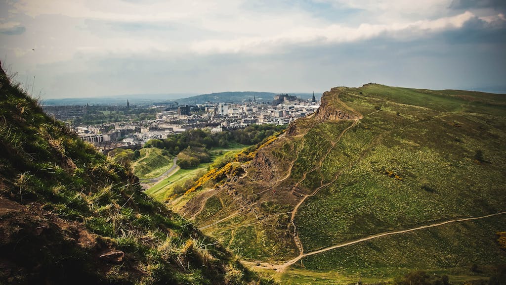 Breathtaking view of Edinburgh cityscape from Arthur's Seat, showcasing lush green landscapes and historic buildings.